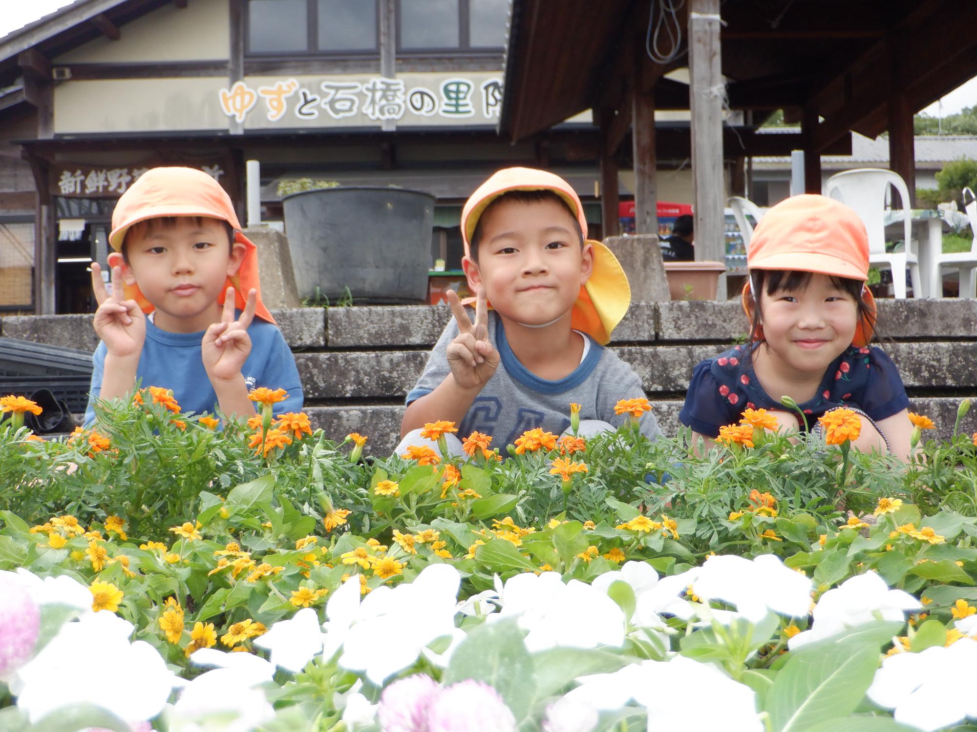 花壇の前で撮影、白い花黄色い花紫の花、年長の子ども達、