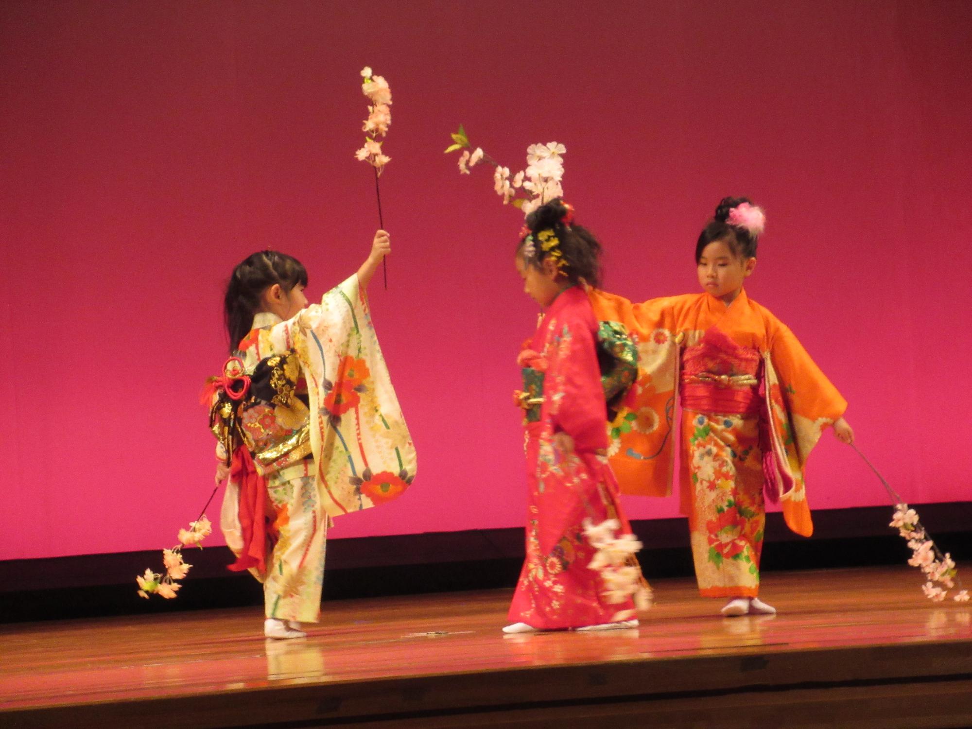 年長の女の子着物姿で桜をもって、舞台に立ってます。