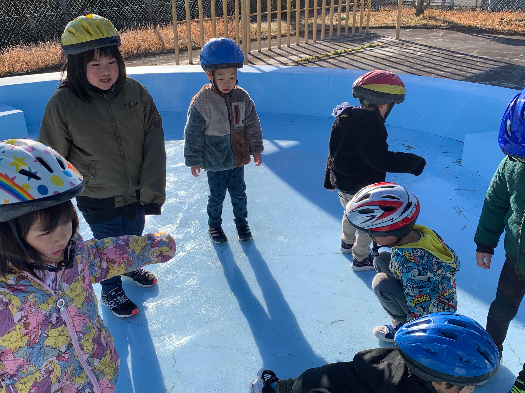 プールに少し水を張って、スケートリンクにしました。ヘルメットをかぶりスケートをする子どもたち