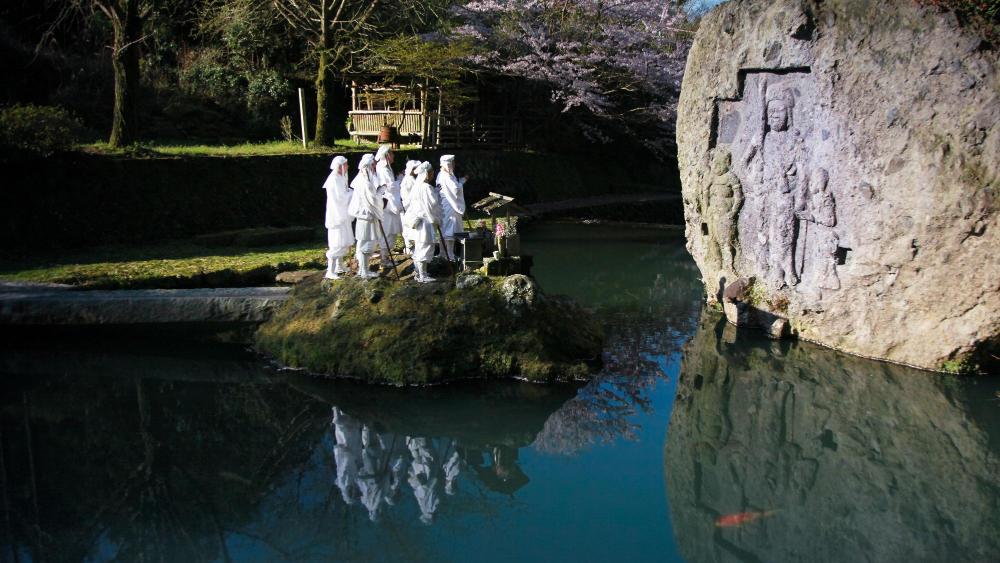 Praying before the Kawanaka Fudo rock carving of Buddhist deities