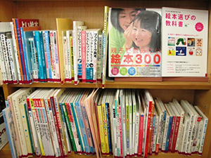 本棚に沢山の本が背表紙で並んでいる状態と右上2冊の本は背表紙で並べられている写真の画像
