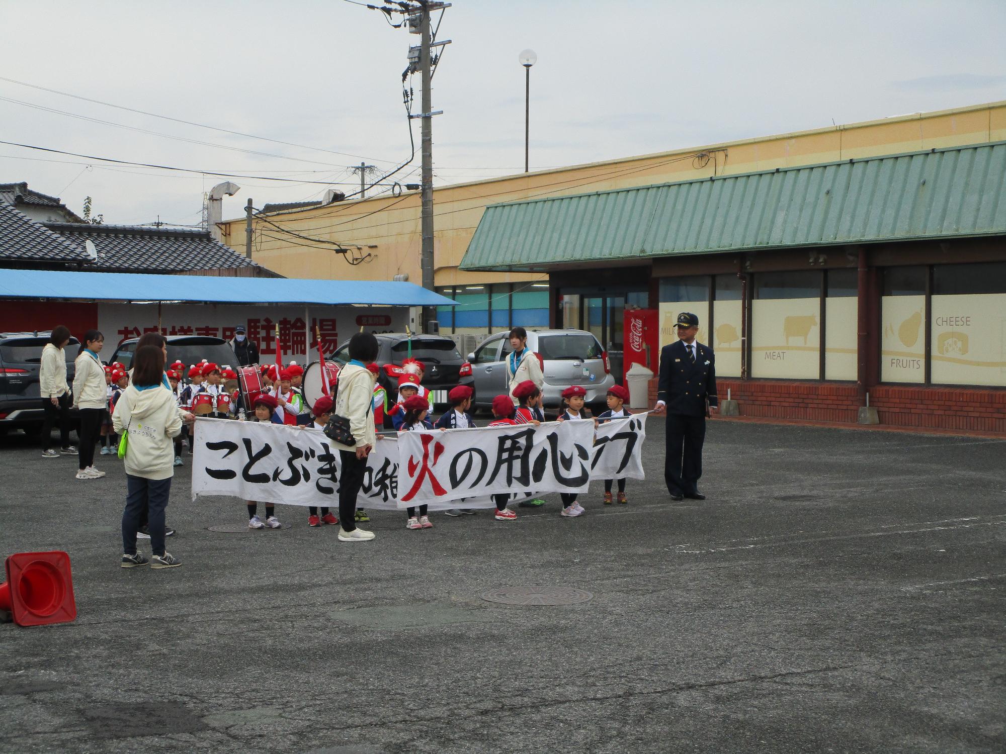 園児たちが横断幕を持ちマーチングをしている写真