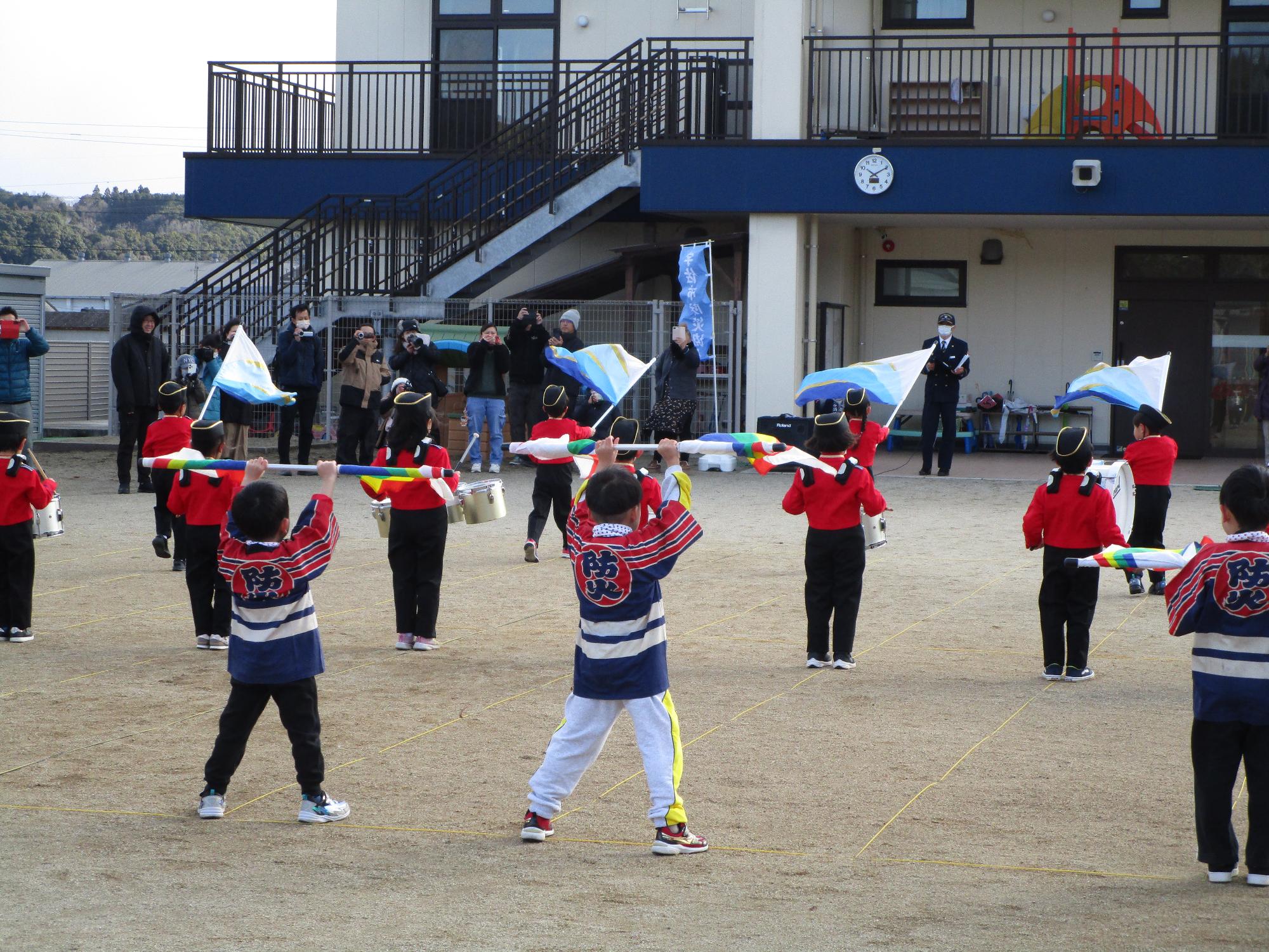 鼓笛演奏に合わせて旗を振る園児たちの写真