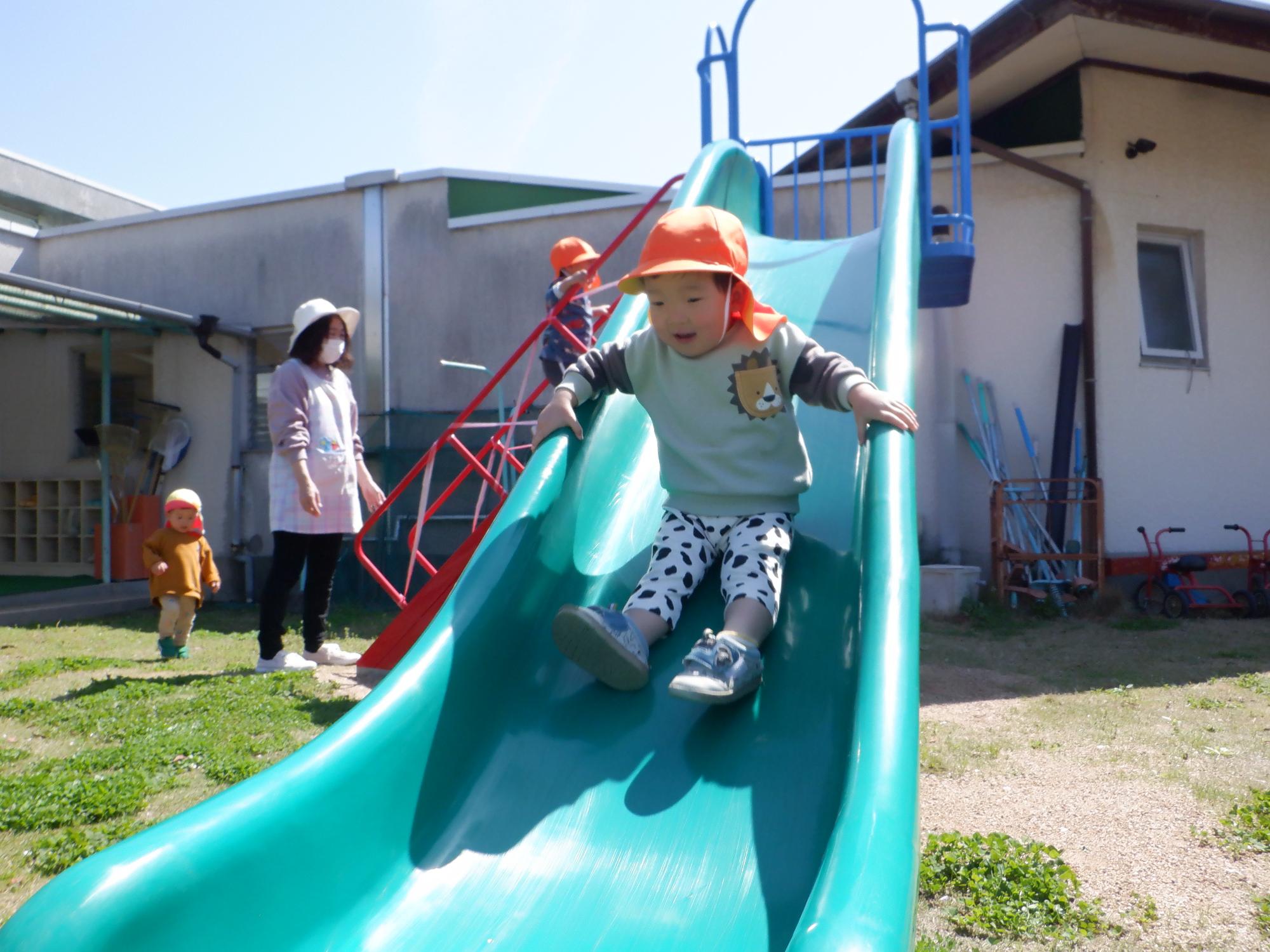 新しい滑り台を滑る2歳の男の子