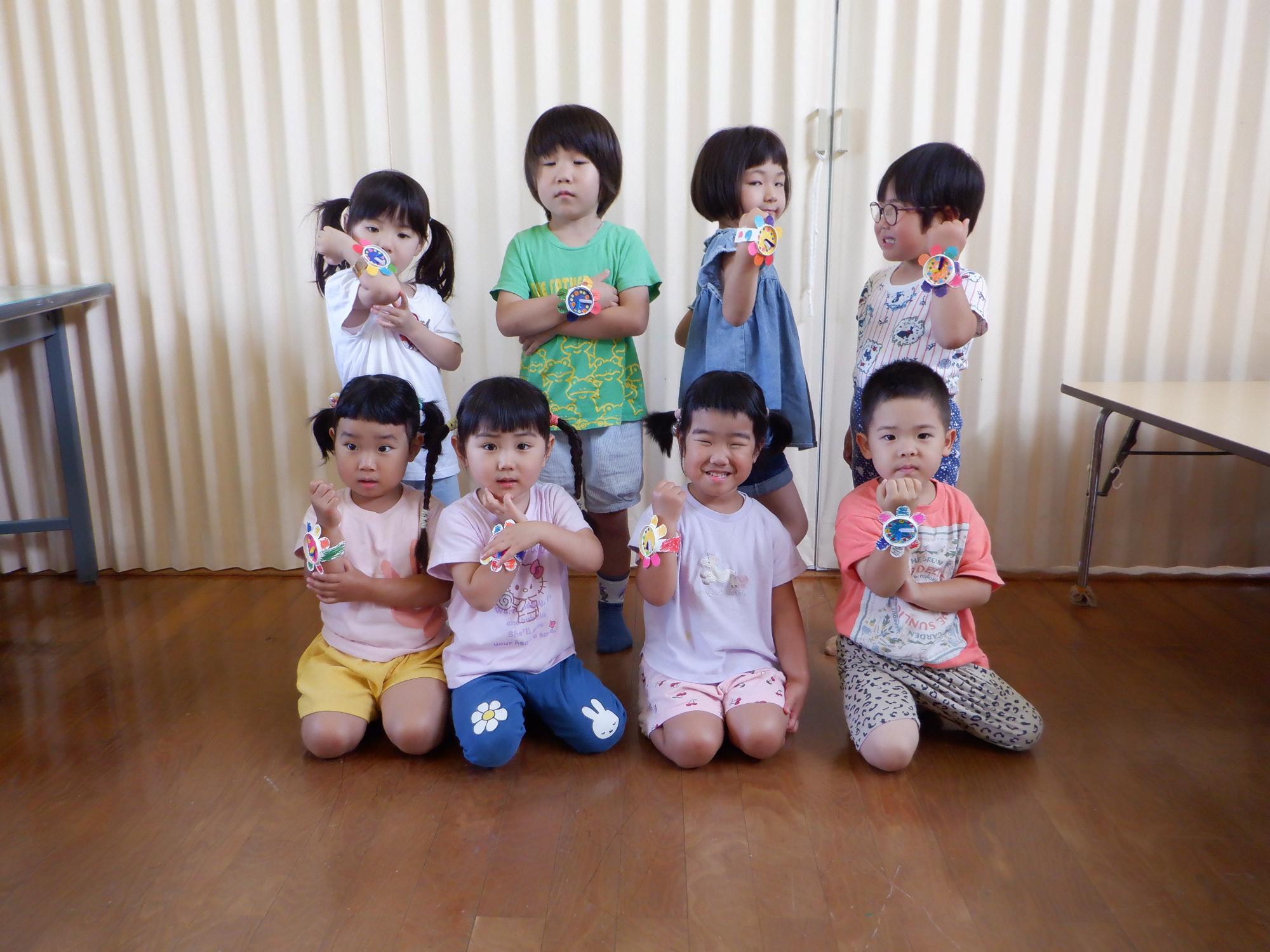 時の記念日の時計を作りポーズ、腕時計をはめた子ども達、