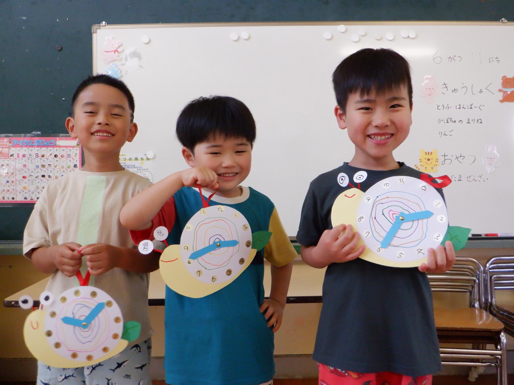 男の子3人、かたつむりの掛け時計を持っている、
