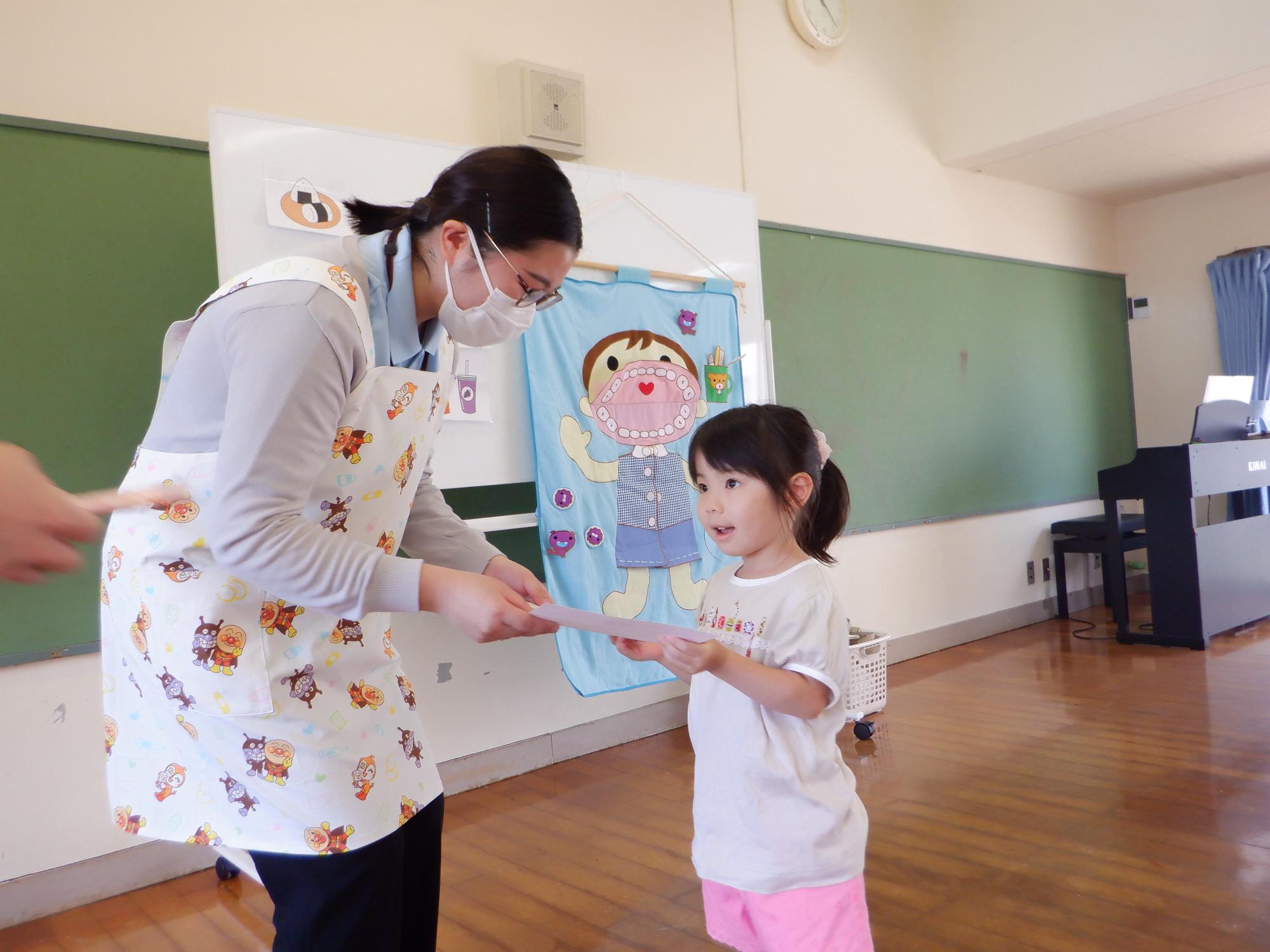 虫歯の無かった子どもの表彰、保健師さんから賞状を貰う子ども