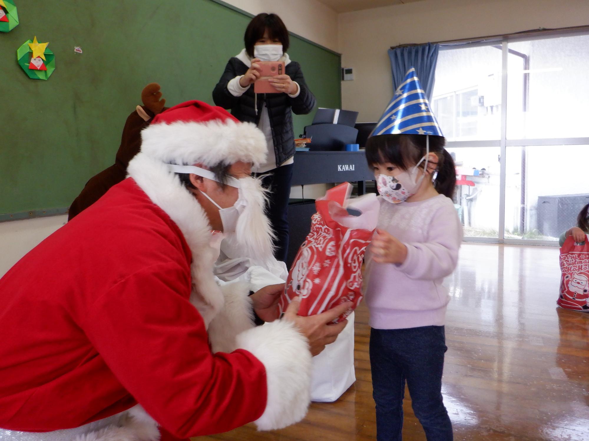 サンタさんにプレゼントをもらう子ども