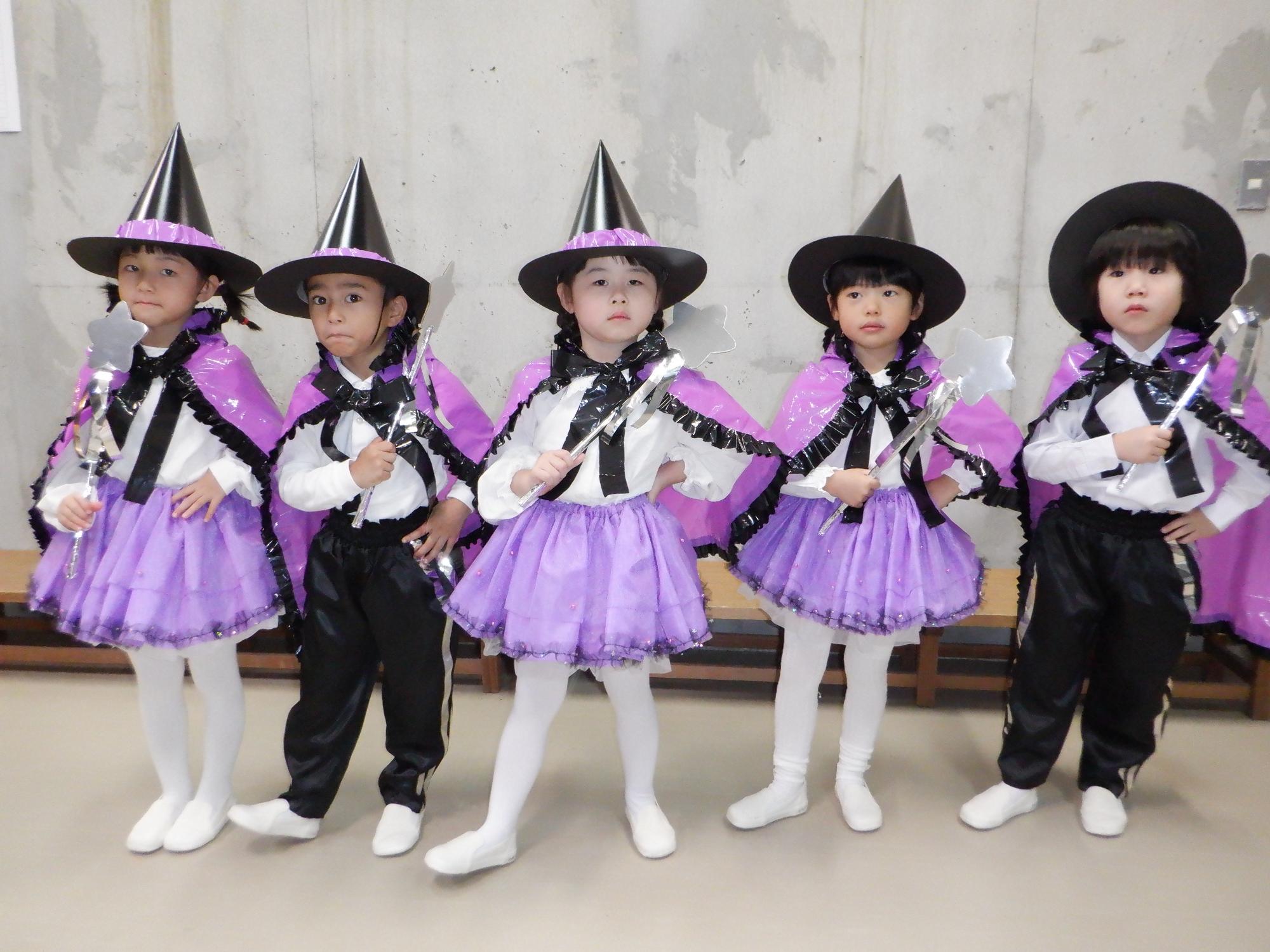 魔法使いの男の子と女の子、紫色と黒の衣装、星のステッキを持っている