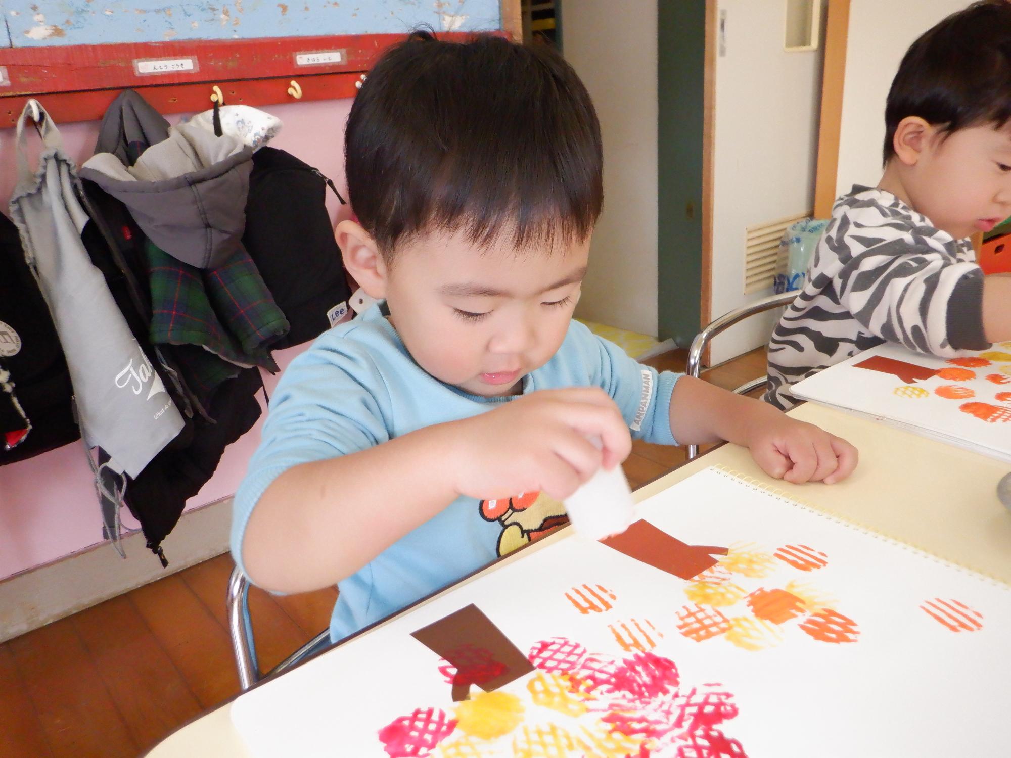 子どもが紅葉の木をスタンピングする、赤黄色オレンジ色のスタンプ