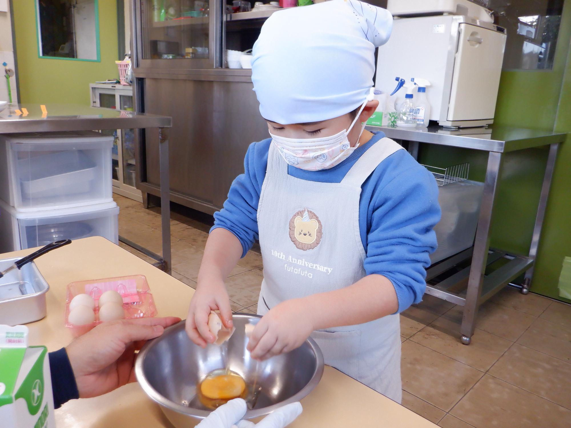 子どもが卵を割っている、ボールに殻も入らず上手に割入れている
