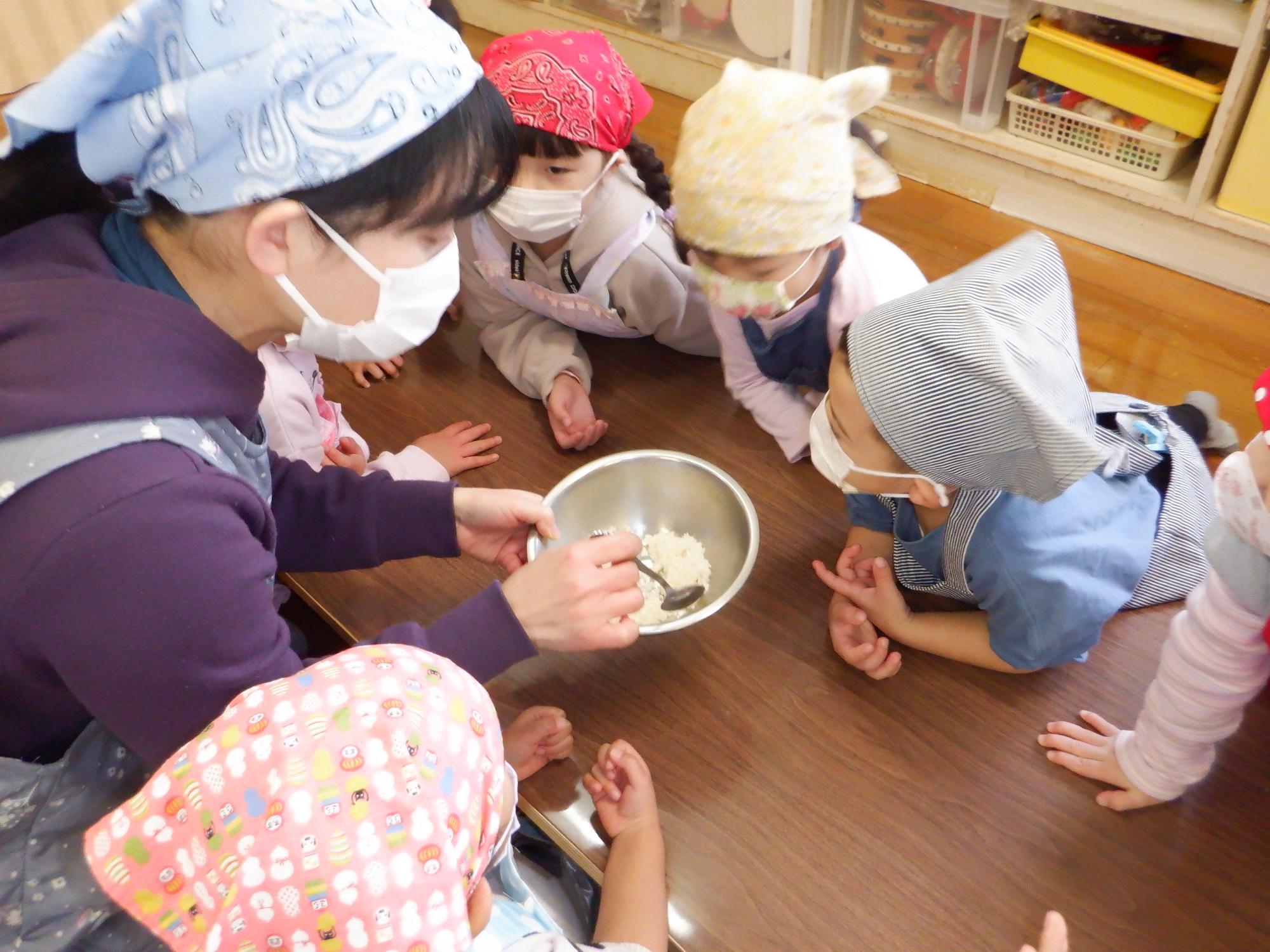 蒸しあがった餅米を見る子ども達、白ご飯との違いに興味津々