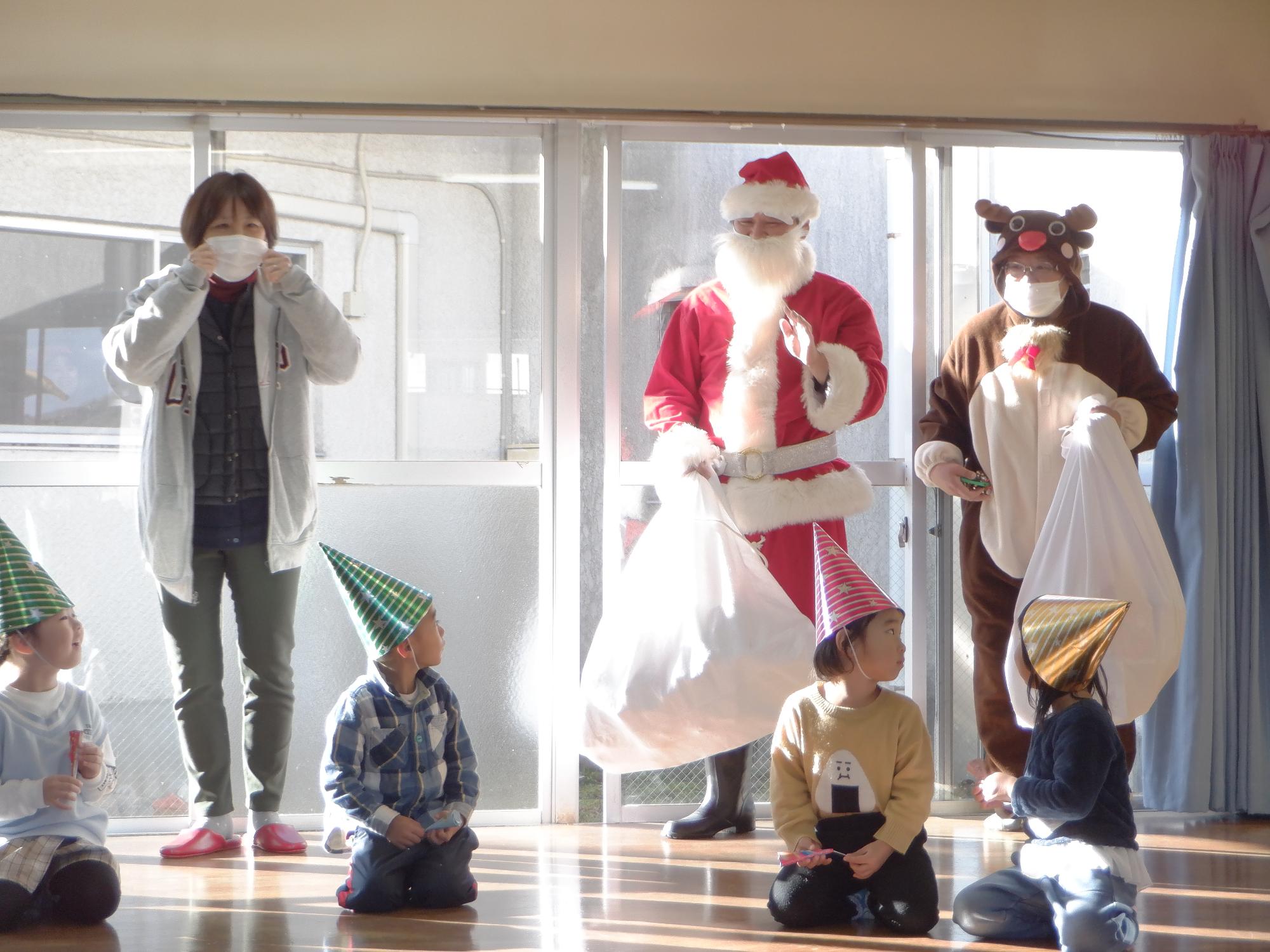 サンタとトナカイ変身した人、子どもたちはびっくり見つめている