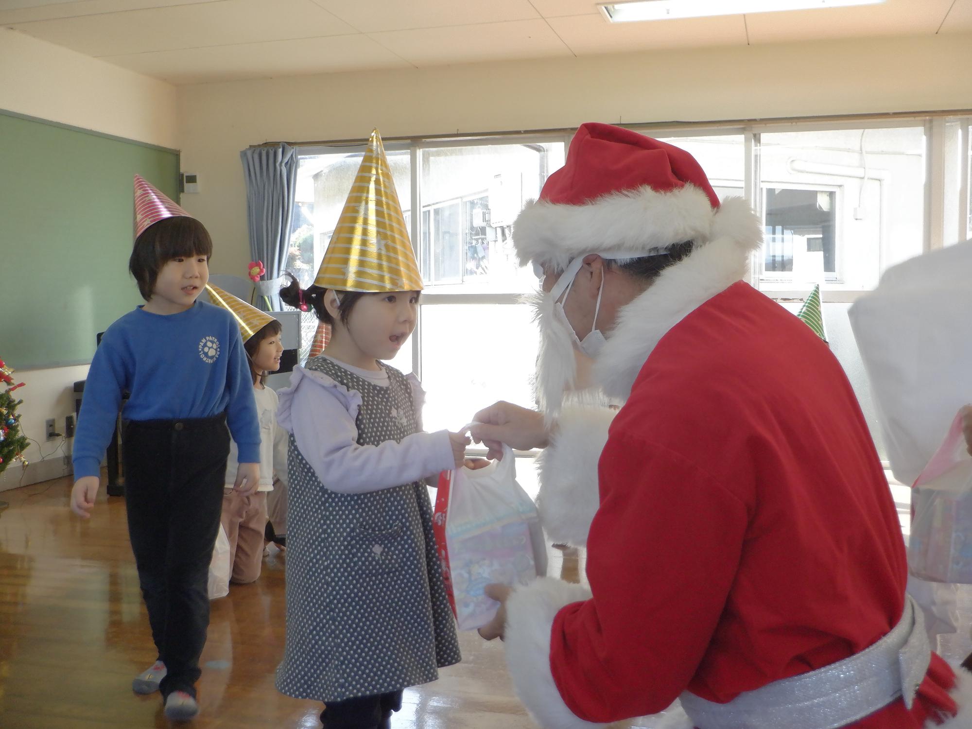 サンタさんからプレゼントを受け取る子ども、嬉しそうにしている子供たち