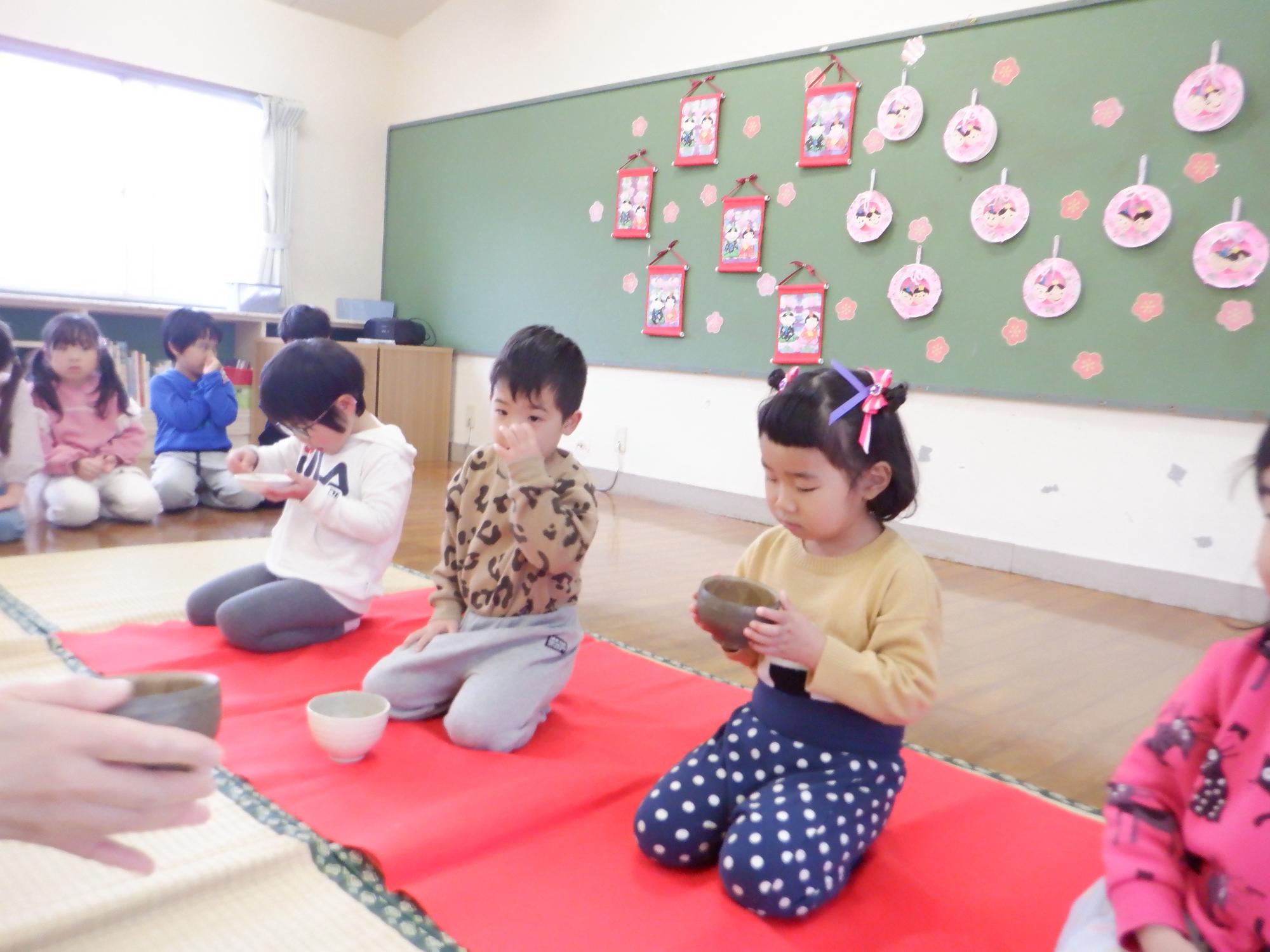 お茶会で茶器でお茶を飲む子ども、正座をしてお行儀良く座っている