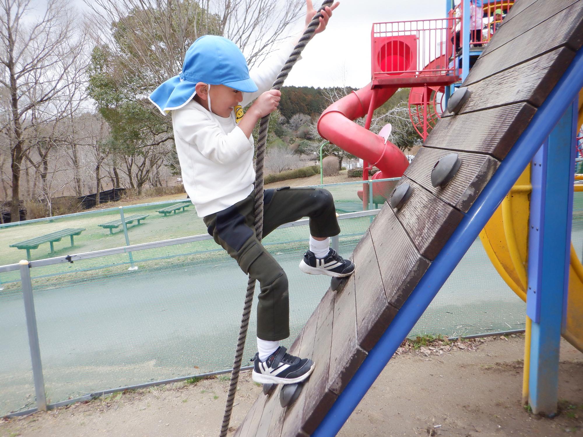 ロープで坂を上る子ども、笑顔で登っている男の子