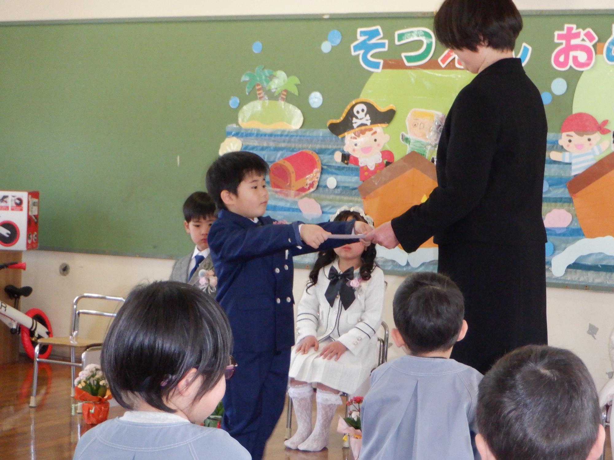 保育証書を受け取る子ども、園長先生から証書を授与される男の子