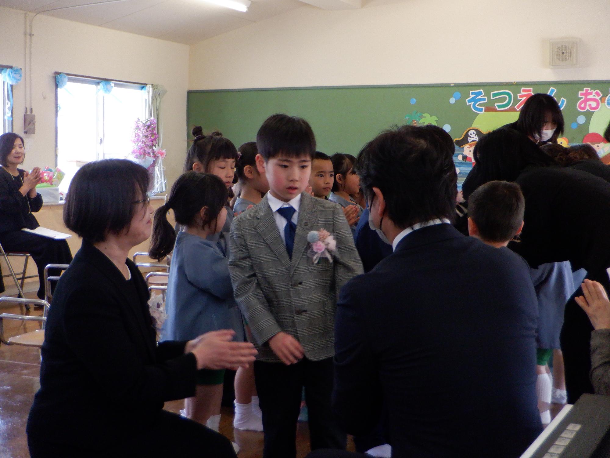 卒園児が在園児の花道を歩いている