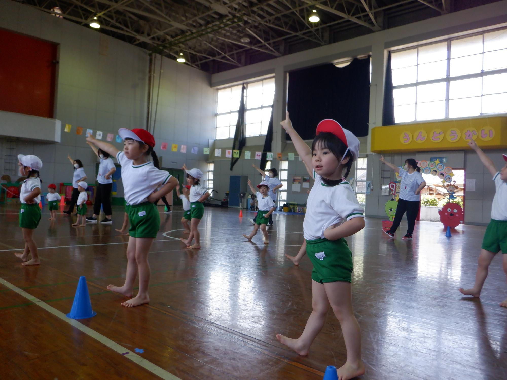開会式、いっとうしょう体操をする子ども、緑の体操服に赤白帽子