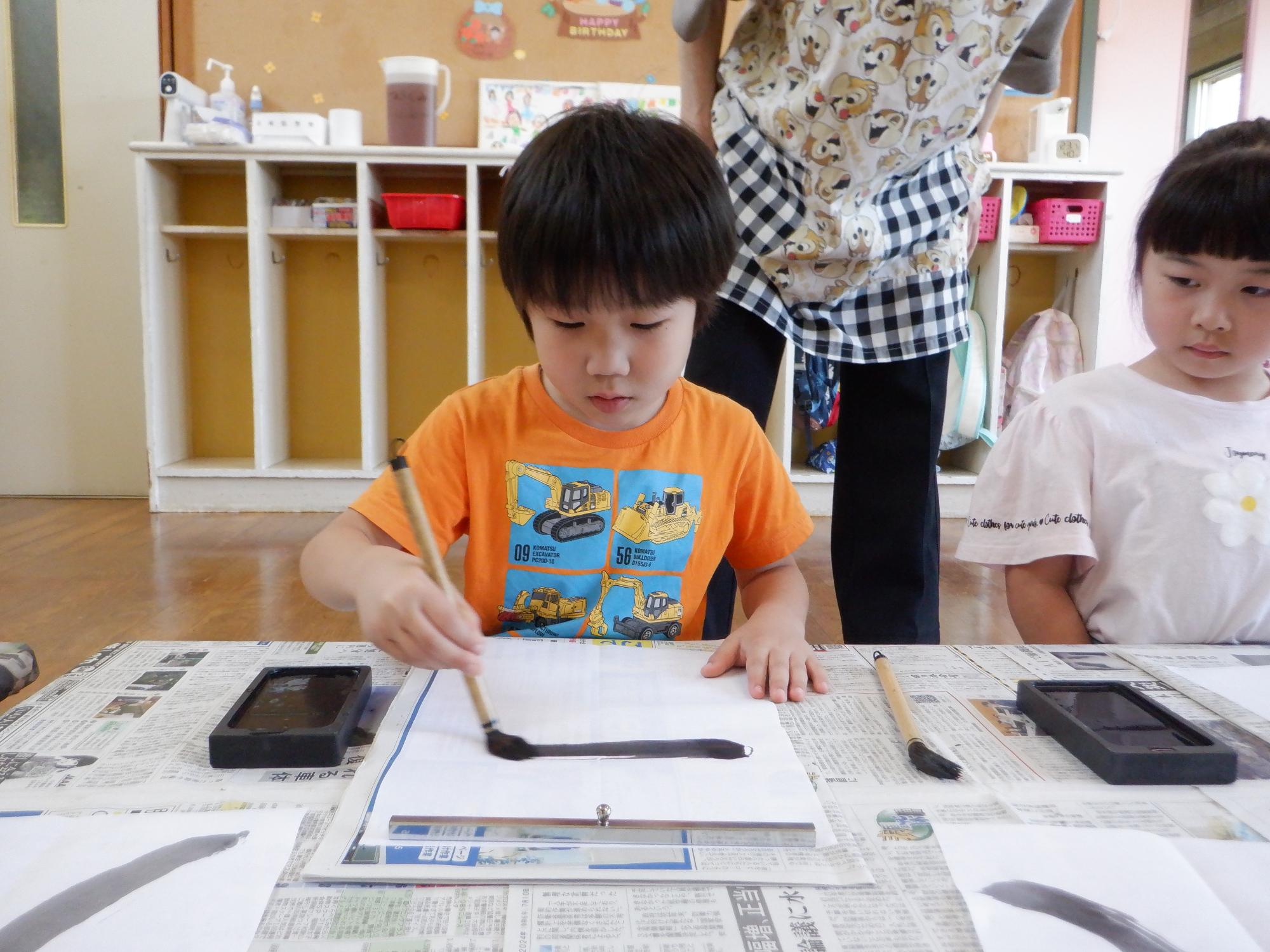 習字をしている男の子、しっかり横ぼうを書いている