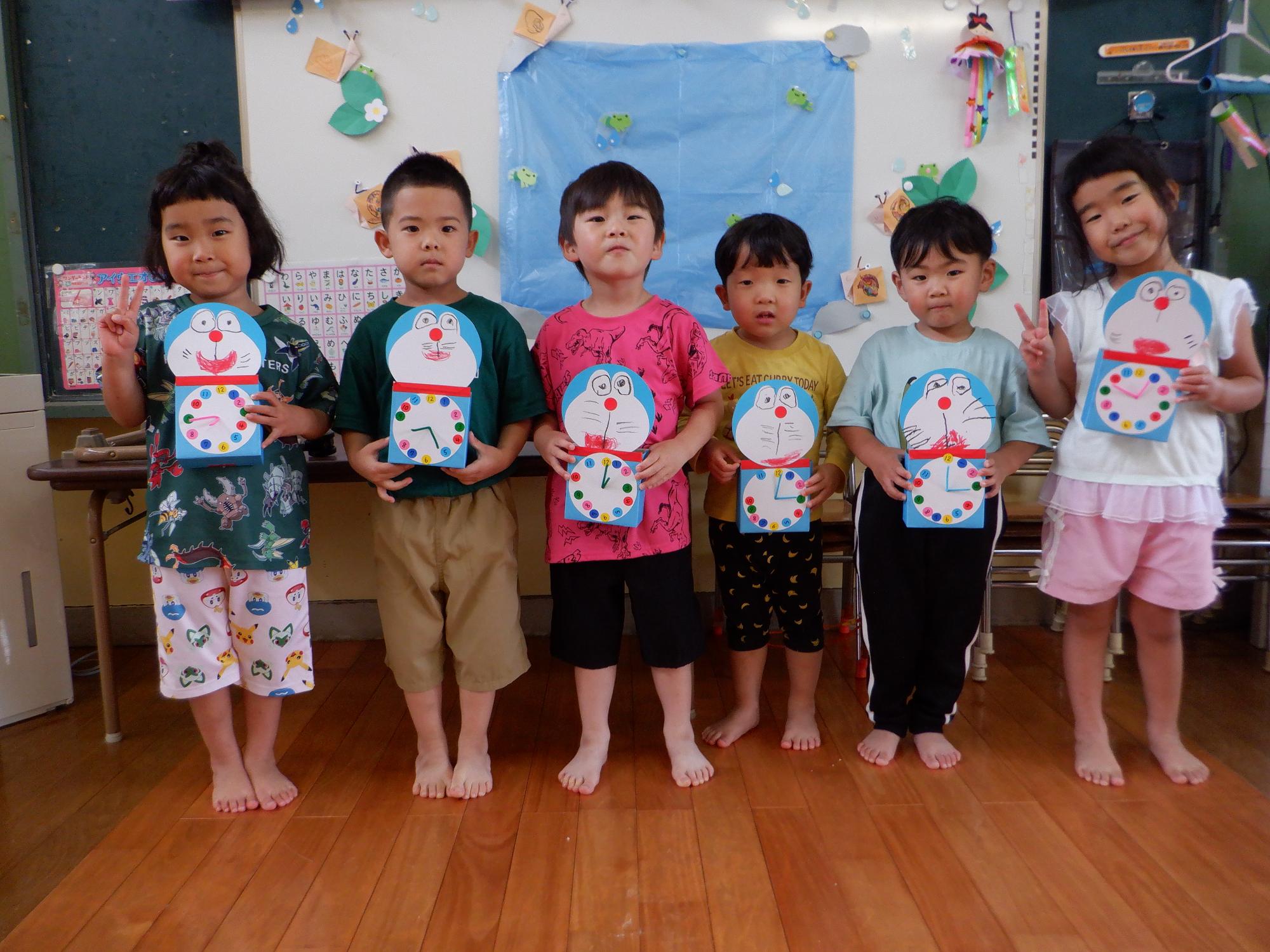 ドラえもんの時計を手作り、時計を持ってうれしそうに微笑む子どもたち
