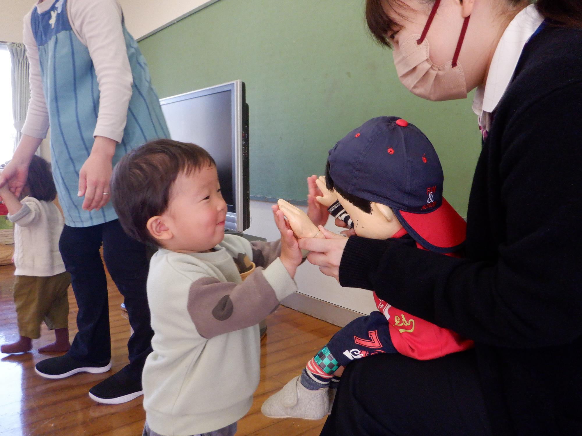 まもるくん人形とハイタッチをする2歳の男の子