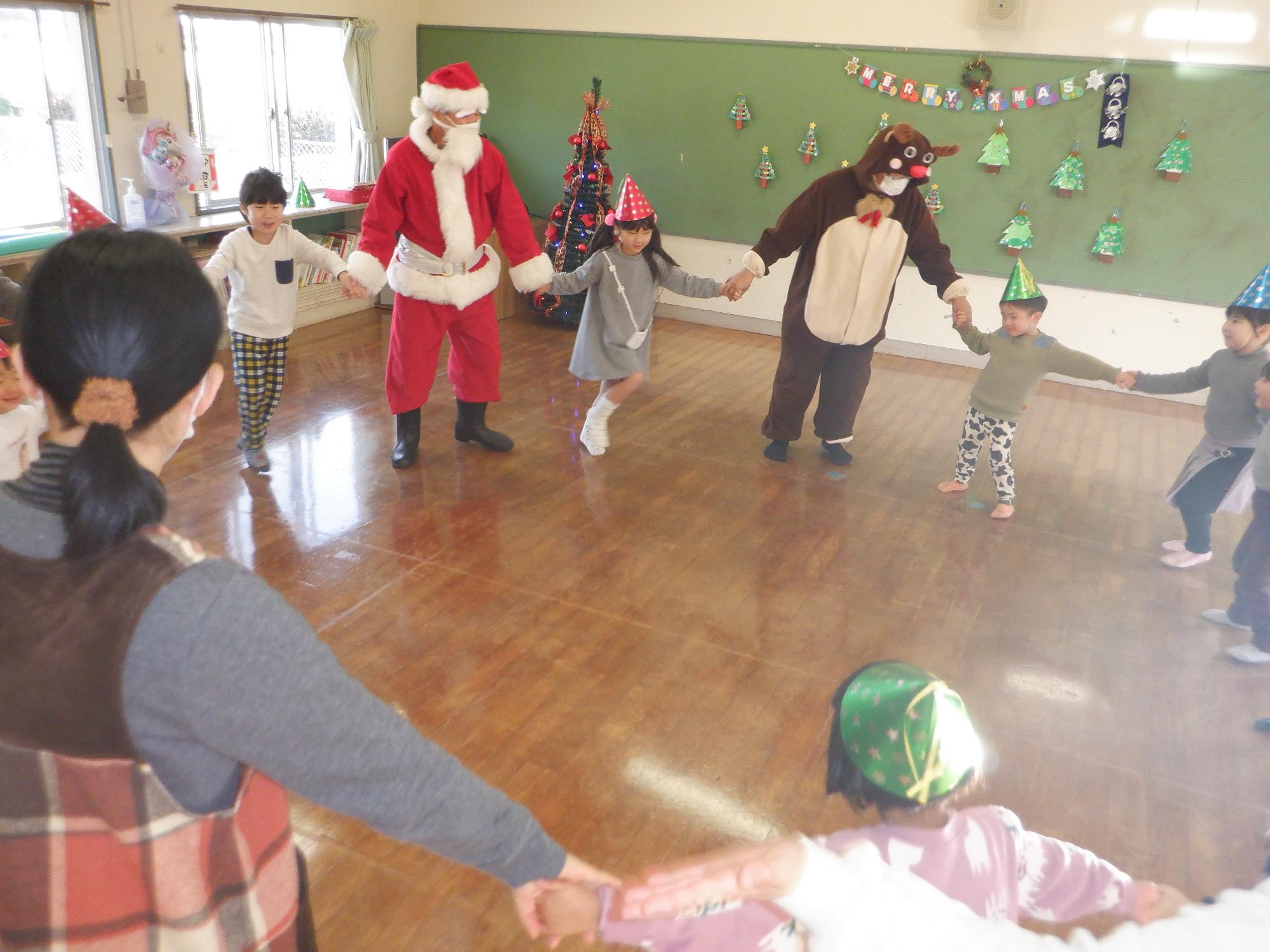 サンタさん、トナカイさんとクリスマスダンスを踊る子どもたち