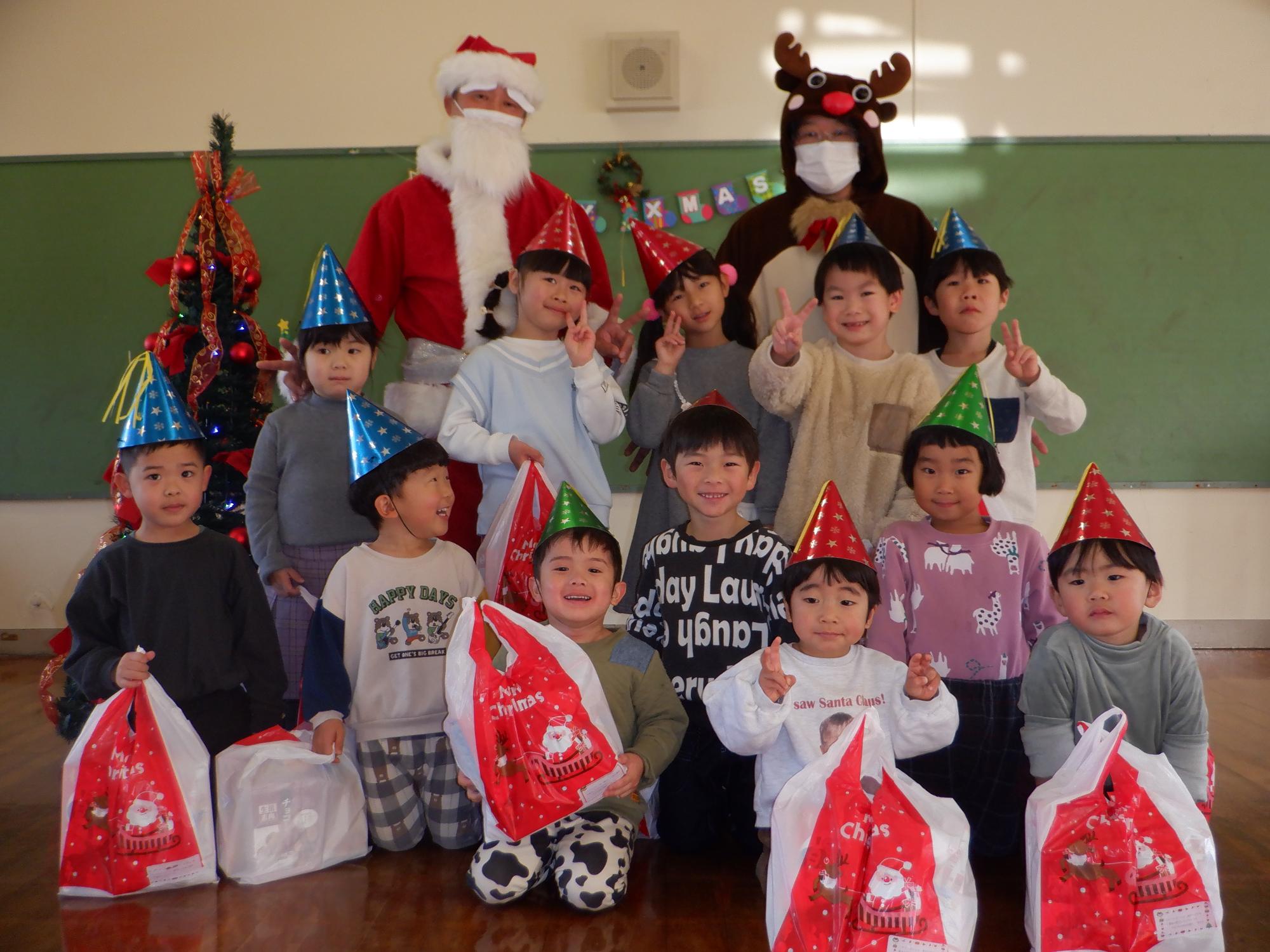 クリスマスプレゼントを持ち嬉しそうにしている子ども、サンタさんトナカイさんと一緒に写真撮影