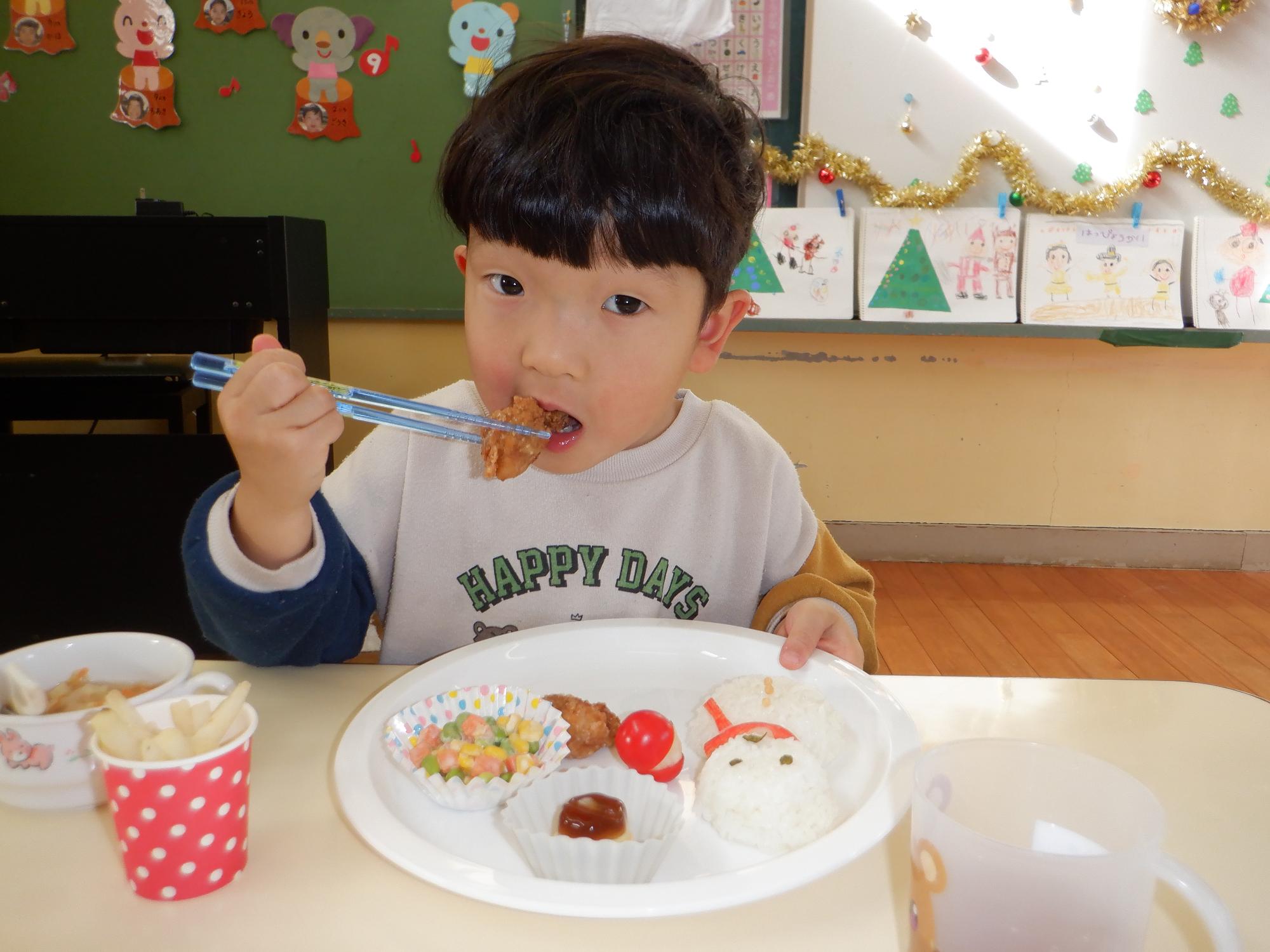 クリスマスのプレートランチを食べる男の子、口を大きく開けて食べている