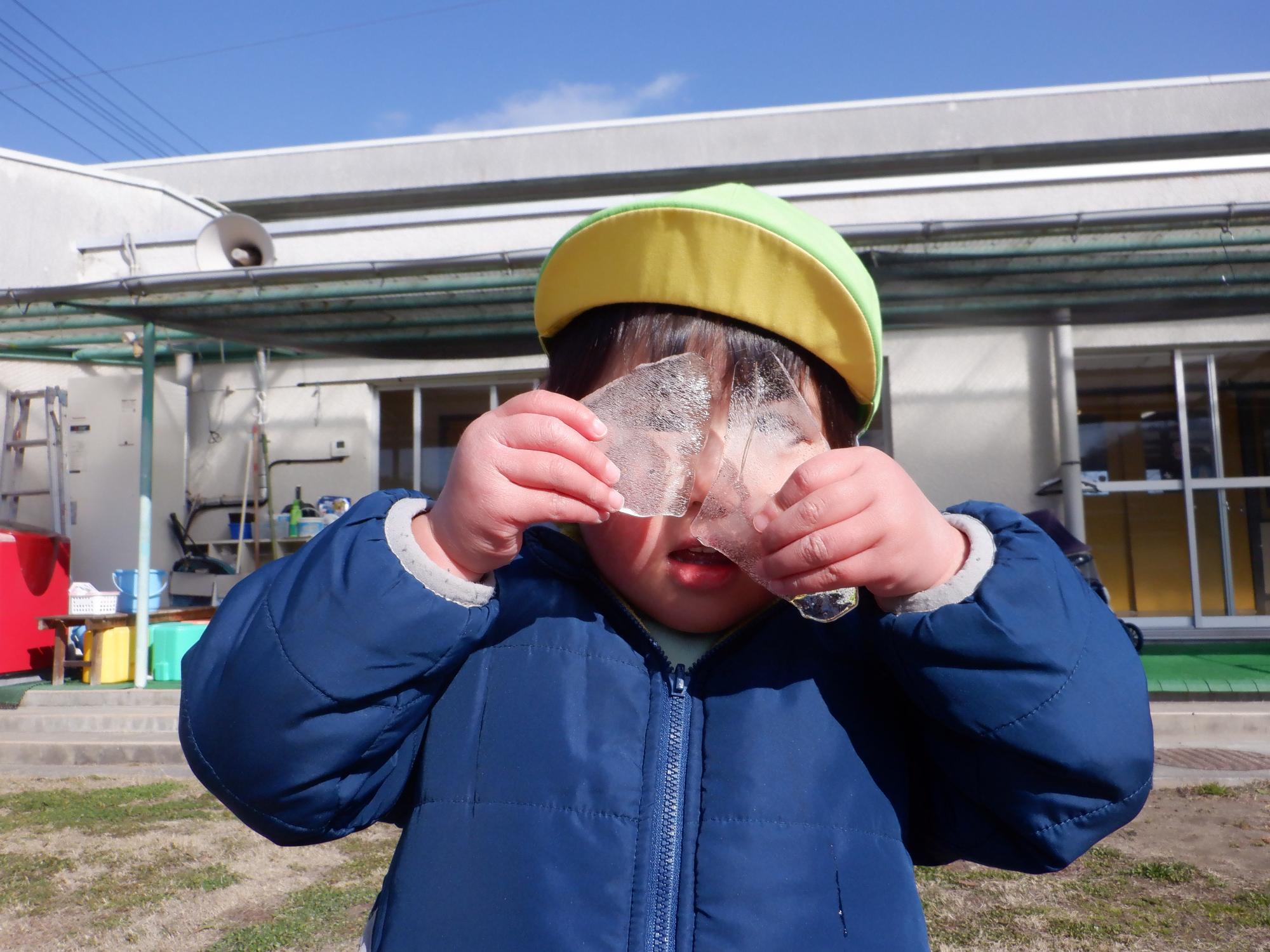 小さな氷を二つメガネのように前に掲げている。