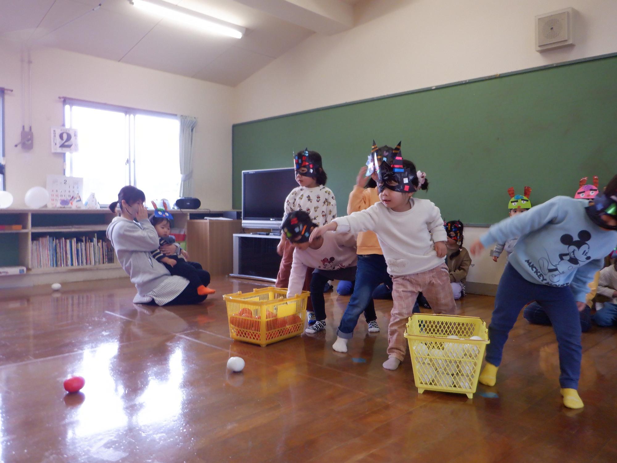 子ども達がボールを投げている、「鬼は外」鬼のボードに向かって赤白のボールを投げる。