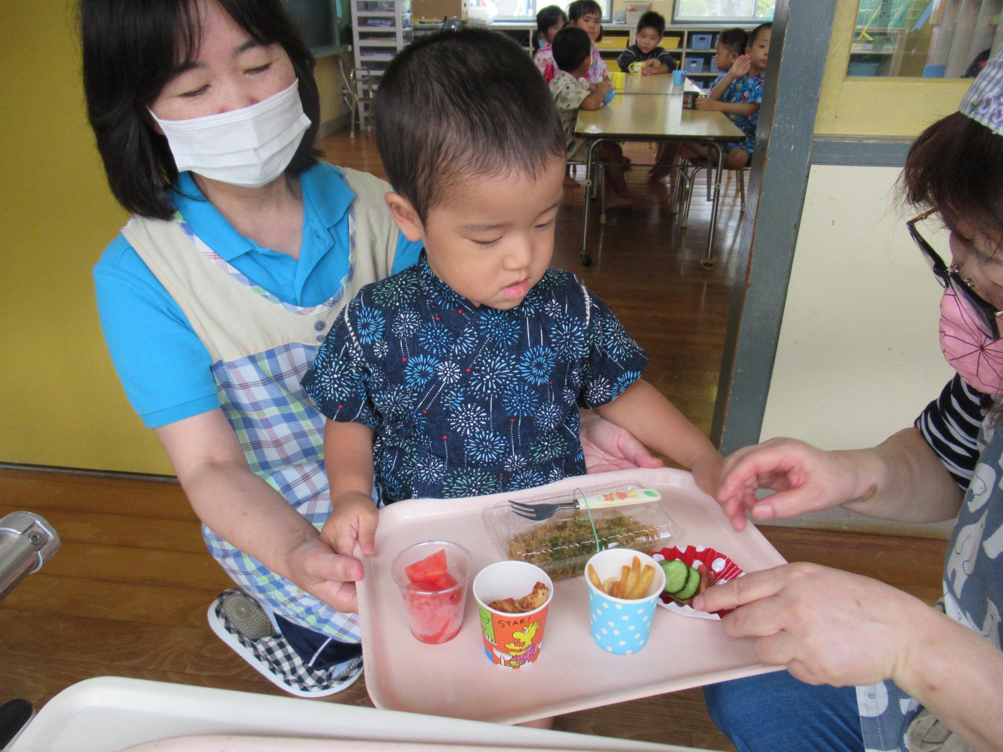 お盆に給食をもらっている様子