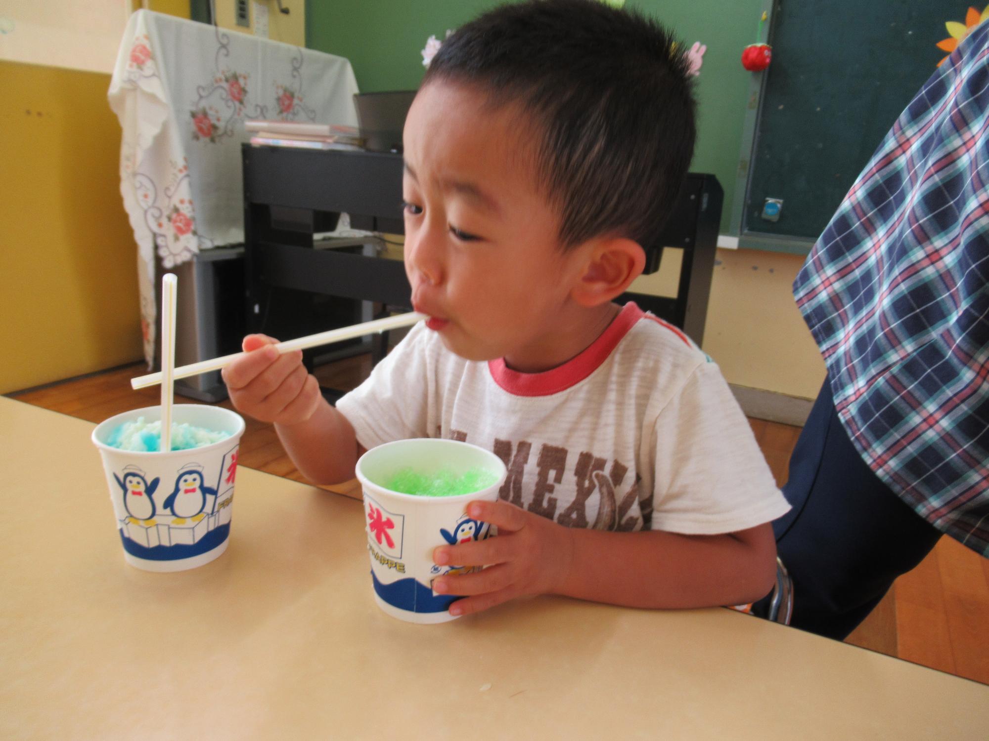 かき氷を冷たそうに食べる子ども