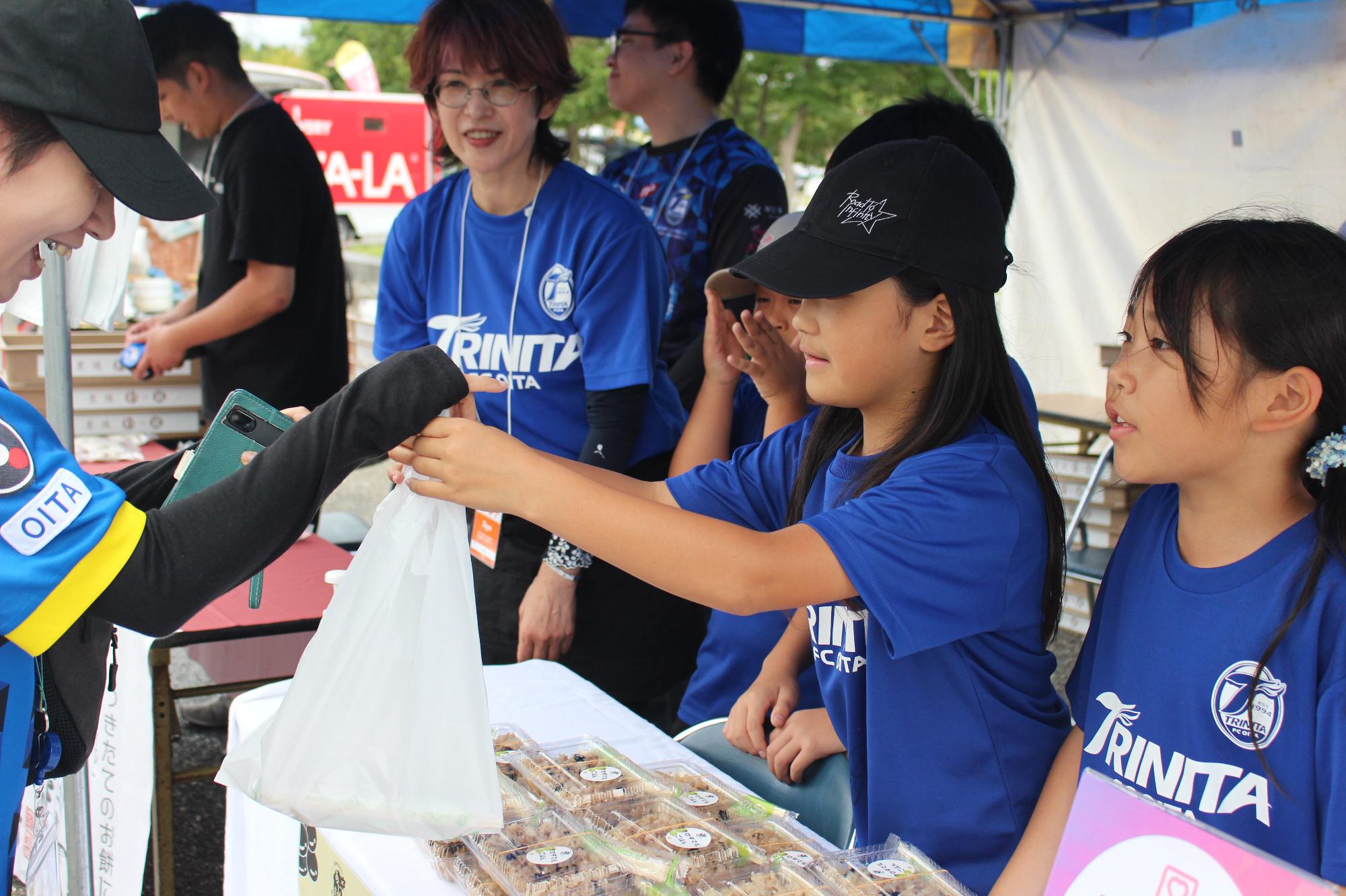 枝豆ごはんをお客さんに手渡す児童