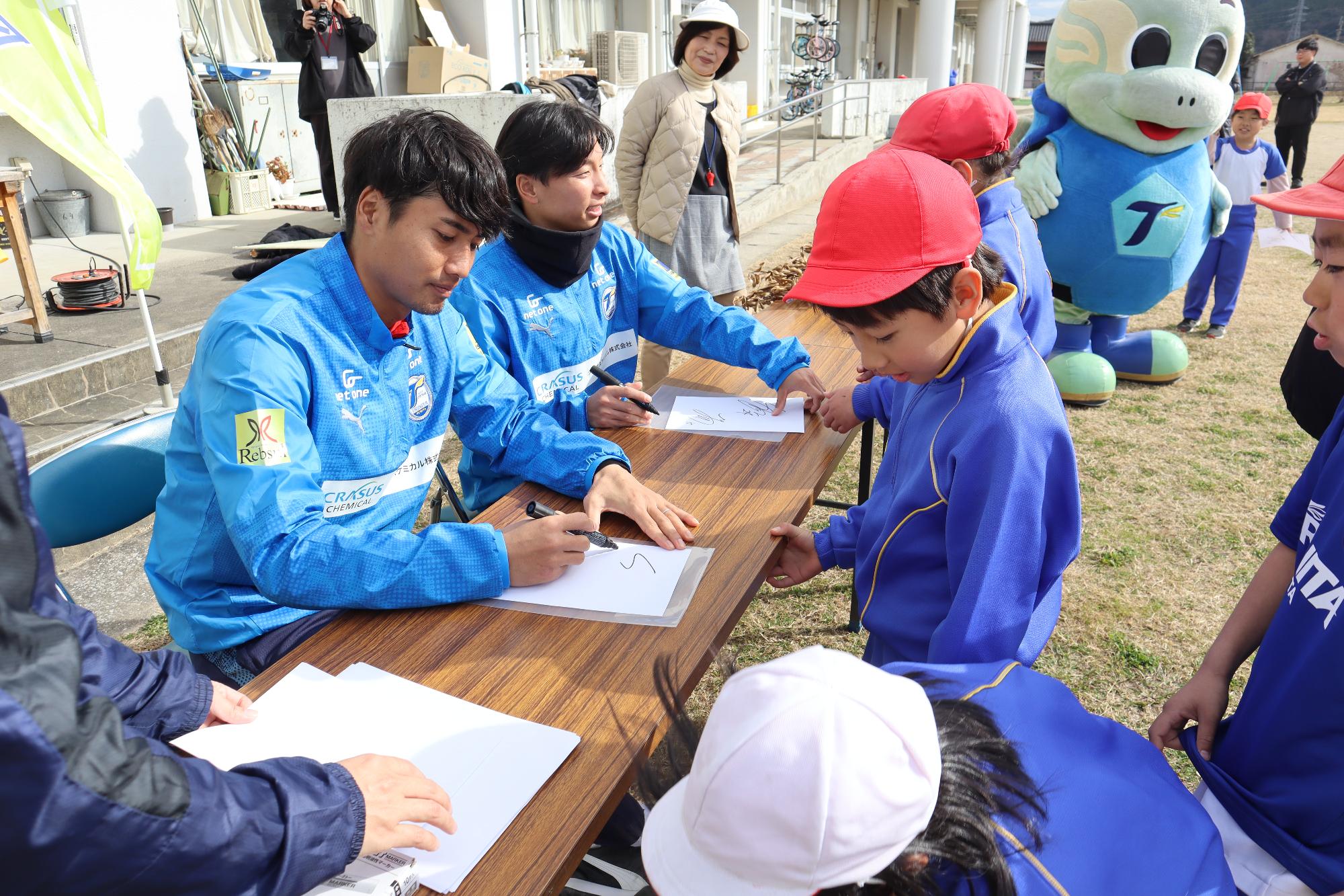 児童にサインを書く両選手