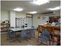 4つの灰色の椅子が奥の白いテーブルを囲むようにしたせせらぎ教室の一室の写真
